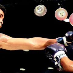 Cassius Clay, som Muhammad Ali, levererar en kraftfull högerkrok mot sin motståndare i en intensiv boxningsmatch.
