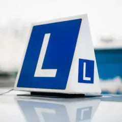 Tablica z literą "L" na dachu samochodu. Zastanawiasz się, ile kosztuje prawo jazdy?