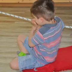 Chłopiec ćwiczy obniżone napięcie mięśniowe w jamie ustnej, bawiąc się sznurkiem.