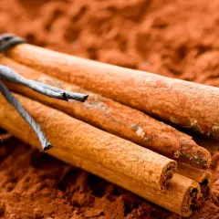Bastoncini di cannella legati con spago su polvere di cannella, spezia nota per le sue proprietà sessuali.