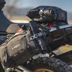 Borsa roll bag nera fissata sul retro di una moto da enduro, pronta per un'avventura.