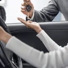 Kluczyki do nowego auta przekazuje sprzedawca, a klientka zastanawia się: leasing czy gotówka?