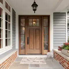 A beautiful front door makeover featuring a warm wooden door with glass panels, flanked by windows. A bird-themed doormat welcomes guests.