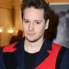 Krzysztof Zalewski, znany z charakterystycznego stylu, prezentuje się w stylowej marynarce. Jego wzrost jest imponujący, a spojrzenie przyciąga uwagę.