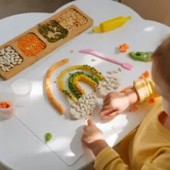 Dziecko tworzy tęczę z plasteliny i ziaren. Powstaje kolorowa zabawka sensoryczna diy.