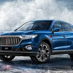 Niebieski Hongqi H5 na skalistym wybrzeżu, z potężnymi falami rozbijającymi się za nim.