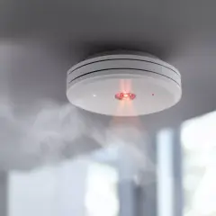 Rauchmelder mit rotem Licht und Dampf. Ein Fehlalarm bei Rauchmeldern kann teuer werden, aber Sicherheit geht vor.