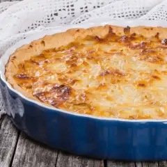 Quiche lorraine dorée dans un plat bleu. Le temps de cuisson et la température parfaits pour un délice croustillant.