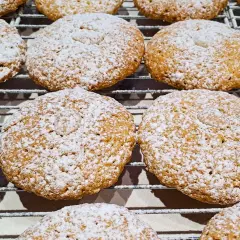 Biscotti con farina di mandorle, cosparsi di zucchero a velo, riposano su una griglia.