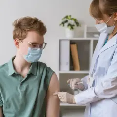 Młody mężczyzna w masce i okularach otrzymuje szczepienie. To ważny krok w dbaniu o zdrowie, podobnie jak szczepienia w Kenii.
