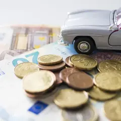 Modellino d'auto su banconote e monete euro. Un promemoria dei costi di gestione, incluso il **super bollo auto**.