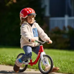 Kleines Kind mit Helm fährt Laufrad. Die richtige Einstellung des Laufrads ist wichtig für den Fahrspaß.