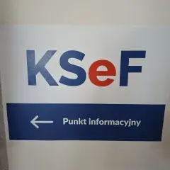 Tabliczka z napisem KSeF i strzałką w lewo do Punktu informacyjnego. Kto wymyślił KSeF? Zapytaj tutaj.