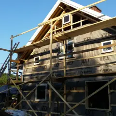 Hus under byggnation med ställningar. Snart dags att måla vindskivor och färdigställa fasaden.