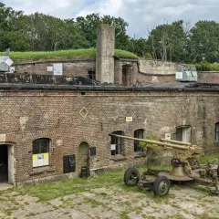 Fort Zachodni z działami na murach i ziemi. Dziecko biega obok zabytkowej broni.