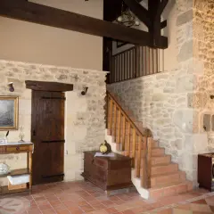 Interior de una casa antigua con paredes de piedra, vigas de madera y una escalera. Un proyecto de reformar casa antigua que conserva su encanto rústico.