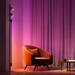 Sofá naranja y cortinas moradas iluminados por luces domoticas, creando un ambiente acogedor.