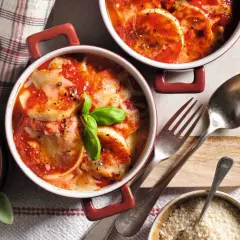 Gnocchi alla Romana ricetta della nonna: dischi dorati al forno, ricoperti di sugo di pomodoro e formaggio filante, guarniti con basilico fresco.