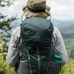 Osoba w kapeluszu z plecakiem Elbrus Moonhill 30 podziwia górski krajobraz.