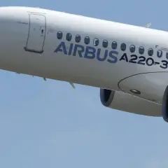 Biały samolot Airbus a220-300 wznosi się na błękitne niebo.