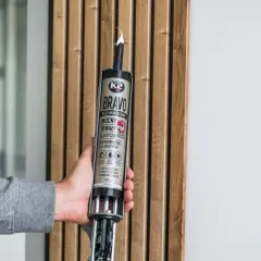 Jak przykleić drewno do ściany? Mocny klej montażowy K2 Bravo z pistoletem w dłoni, gotowy do pracy.