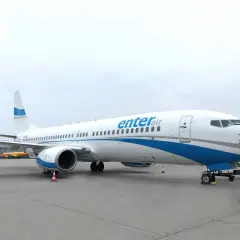 Biały samolot Enter Air z niebieskimi pasami na tle pochmurnego nieba. Gotowy do startu, by zabrać pasażerów w podróż.