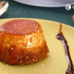 Delicioso flan de coco con caramelo líquido y coco rallado, servido en un plato amarillo.