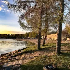 Zachód słońca nad jeziorem, plaża i budynek z tarasem. Skorzęcin atrakcje czekają na turystów.