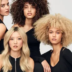 Fyra kvinnor med olika hårtyper: rakt, lockigt och afro. Alla har slitet hår som ser friskt ut.