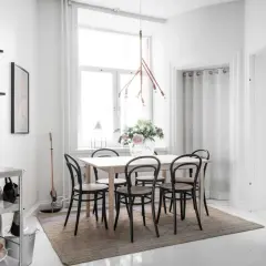 Ljust och luftigt kök med matbord och stolar, perfekt för matbord inredning inspiration. En stor vas med blommor pryder bordet.