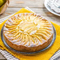 Torta di mele senza zucchero, decorata con fettine di mela disposte a raggiera e spolverata di zucchero a velo.