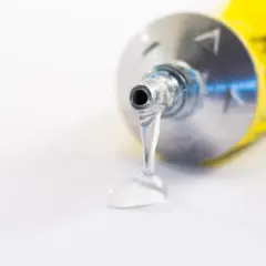 Goutte de colle polyuréthane sortant d'un tube métallique. Utile pour enlever colle polyuréthane tenace.