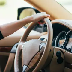 Dłoń na kierownicy, czuć drgania na kierownicy przy 100 km/h. Wnętrze luksusowego samochodu.