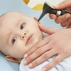 Un medico esamina l'orecchio di un neonato con un otoscopio. È importante controllare i bambini per l'otite.
