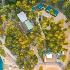 Malowniczy camping w Małopolsce nad turkusową wodą. Domyki, budynki i samochody wśród jesiennych drzew.