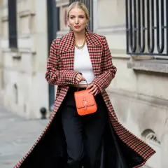 Elegancka kobieta w długim, kraciastym płaszczu damskim, z pomarańczową torebką.