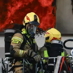 Dwóch strażaków w akcji, walczących z ogniem. Zastanawiasz się, ile zarabia młodszy kapitan w straży pożarnej?