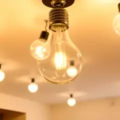 Un plafón con varias bombillas colgantes, algunas transparentes y otras opacas, iluminan cálidamente el techo.