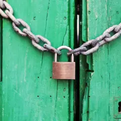 Puerta verde cerrada con cadena y candado. Un símbolo de que se puede quitar el usufructo de una vivienda.