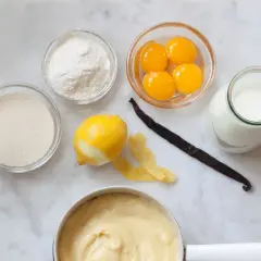 Składniki do kremu patissiere: żółtka, cukier, mąka, mleko, cytryna, laska wanilii i gotowy krem.