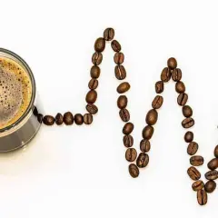 Tazza di caffè con chicchi disposti a formare un elettrocardiogramma, simbolo della caffeina nel caffè che stimola il cuore.