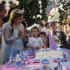 Celebración de cumpleaños en aula infantil con pastel de Frozen y niños emocionados.