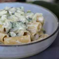 Pasta con calabacín cremosa, servida en un cuenco. Los trozos de calabacín se mezclan con la pasta y una salsa blanca.