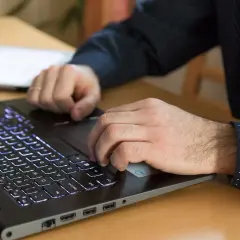 Dłonie pracują na podświetlanej klawiaturze laptopa, korzystając z funkcji biometrii do logowania.