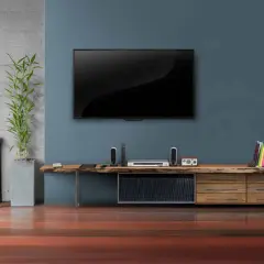 Moderner fernseher im wohnzimmer, daneben ein schlichtes Sideboard mit Deko und Büchern.
