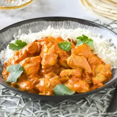 Un delicioso pollo tikka masala receta servido con arroz basmati y cilantro fresco.