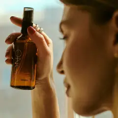 Kobieta trzyma buteleczkę z mgiełką, która zawiera alkohol cetylowy. Delikatna pielęgnacja dla skóry.