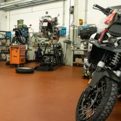 Officina moto con diverse moto in lavorazione. Un tecnico si chiede ogni quanto si fa il tagliando per mantenere al meglio il proprio mezzo.