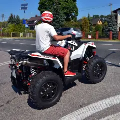 Mężczyzna w kasku na quadzie Polaris na drodze. Czy na quadzie trzeba mieć kask? Tak, dla bezpieczeństwa!