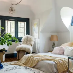 A cozy bedroom with a fluffy chair, plush pillows, and a soft throw blanket. Learn how to create a cozy bedroom with these inviting elements.